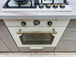 In a warm and inviting kitchen, a stylish sleek white oven is elegantly placed atop a modern gas stove, significantly enhancing both functionality and overall style within the cooking space photo