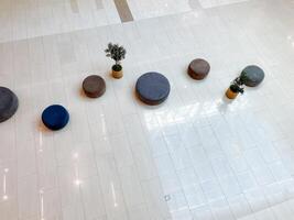 A collection of traditional ottomans with vibrant plants on a tiled floor creates a cozy, inviting atmosphere in this delightful space for all who enjoy its warm ambiance photo