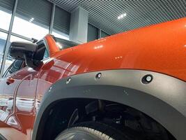 This image features a detailed closeup of a striking orange car that is prominently highlighted with stylish black fender flares, showcasing its impressive design and color contrast photo