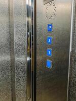 This stainless steel elevator features blue buttons labeled for parking P, second floor 2, and entrance level 1, ensuring efficient control of the buildings floors photo