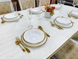 A beautifully arranged dining table set featuring elegant white plates accompanied by luxurious gold silverware, creating an inviting and sophisticated atmosphere for any meal photo