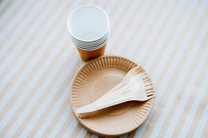 A simple paper plate featuring a fork and spoon carefully placed on top of it, situated right next to a cup. This setup creates a casual dining experience perfect for any gathering photo