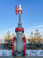 A large valve, complete with a prominent red handle, is positioned on top of a solid concrete surface, creating a striking contrast to its surroundings and emphasizing its importance photo