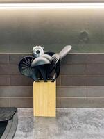 On the countertop, there is a wooden block that is filled with various kitchen utensils, providing convenience and organization in the kitchen while enhancing its overall aesthetic appeal photo