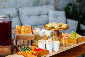 In a cozy living room, there is a table adorned with a diverse variety of food options and an array of drinks, creating an inviting atmosphere for socializing and enjoyment photo