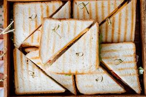 A delightful collection of mouthwatering, delicious sandwiches is artfully stacked in a rustic, charming wooden box, eagerly waiting to be enjoyed by anyone who happens upon them photo