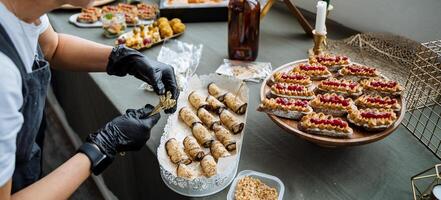A person who is wearing black gloves is carefully and meticulously preparing food on a table, ensuring that all ingredients are properly handled, organized, and ready for the upcoming meal photo