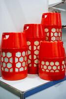 A collection of bright red plastic containers, arranged in a neat stack on top of one another, is resting on a table, creating an interesting visual display of color and form photo