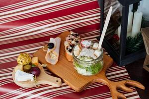 On a beautifully set table, there is a wooden cutting board elegantly placed, which has a jar of delicious food atop it, ready to be enjoyed for a delightful meal experience photo