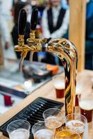 A beer tap steadily pours a frothy, delicious beer into glasses that sit ready on the table, patiently awaiting the arrival of people who will gather to celebrate in joy and camaraderie photo