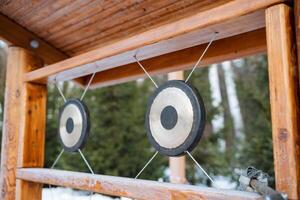 The traditional outdoor gongs are displayed on a rustic wooden frame, beautifully surrounded by nature, creating a vibrant and serene atmosphere for relaxation and creativity photo
