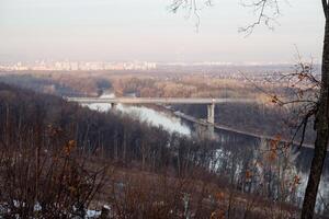 There is a picturesque bridge gracefully spanning across a flowing river, beautifully situated right in the middle of a lush green forest, creating a stunning natural landscape photo