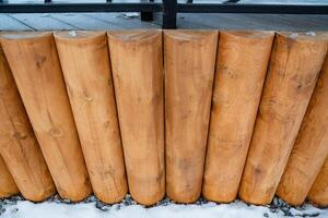 This captivating image features a closeup of a rustic wooden fence made of logs, covered in a soft layer of white snow, enhancing its natural charm and creating a picturesque winter scene photo