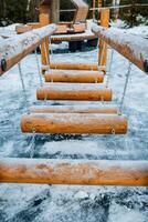 A beautifully crafted wooden bridge stands majestically, completely blanketed in a thick layer of snow and glistening ice, creating a stunning winter scene in the natural landscape photo