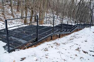 Winding Snowy Path with Sturdy Metal Railings in a Beautiful Forested Area This is a Scenic Winter Hiking Trail that invites adventurers to explore its serene beauty photo