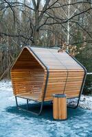 In a picturesque park, there is a charming wooden bench situated right next to a conveniently placed trash can, creating a comfortable and clean space for visitors to relax photo