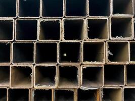 This closeup shows a neatly arranged stack of square metal pipes, highlighting their robust structure. Made from durable steel, these pipes are essential building materials photo