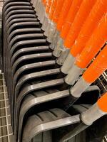 A collection of several shovels, each exhibiting vibrant orange handles, are meticulously stacked one on top of the other in a neat arrangement to save space and maintain organization photo