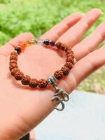 A person is delicately holding a beautiful bracelet that features a pendant engraved with the sacred symbol om, which holds significant meaning in various cultures and religions photo