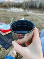 A person is holding a cup that is filled with water in their hand while standing, showcasing the drinkware item against a vibrant backdrop, emphasizing the liquid contained within photo