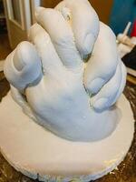 A beautifully crafted statue of two hands clasped together, elegantly placed on a polished wooden tabletop, showcasing exceptional artistry and captivating emotions for all viewers photo