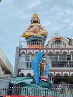 In a picturesque setting, a magnificent statue of a man can be seen sitting elegantly in front of a prominent building, creating a captivating atmosphere for visitors and tourists alike photo