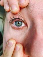 A striking and captivating closeup image showcasing a human eye, where a finger gently touches the eyes surface, representing deep curiosity and personal exploration within oneself photo