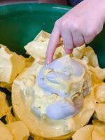 A hand eagerly reaches outward toward a large bowl that is filled to the brim with a delightful assortment of food, trying to grab something delicious from the colorful array of treats photo