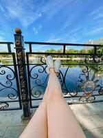 A womans legs are comfortably resting on a beautifully crafted wrought iron railing that overlooks a serene lake, providing a perfect view of nature and relaxation at its finest photo