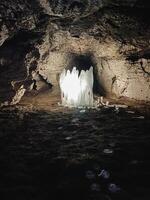 Inside the depths of a mysterious cave, one can find a vast and impressive ice formation that dominates the center of the space, creating a stunning natural spectacle in darkness photo