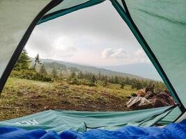 Imagine a beautiful tent set up in a scenic location, offering a stunning view of a lush forest and majestic mountains that stretch across the horizon, creating a tranquil outdoor escape photo