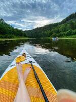 A person is laying on a paddle board in the water photo