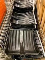 A bunch of durable black plastic shovels are neatly stacked on top of one another on a shelf, showcasing their organized arrangement and practical design for various tasks photo