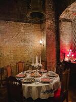In a dimly lit room, there is a beautifully arranged table adorned with elegant plates and flickering candles that create a warm and inviting ambiance, perfect for any special occasion photo