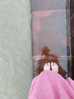 An individual is relaxing comfortably on a soft pink towel, with their feet playfully dipping into the refreshing water, creating a serene and enjoyable atmosphere for relaxation photo