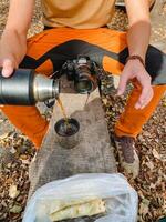 At this very moment, a person is actively pouring a liquid substance from a thermos container into a cup, which can be used for drinking or various other intended purposes photo