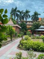 A scenic path leads to a breathtaking temple surrounded by vibrant palm trees and lush greenery, creating a serene atmosphere for all to enjoy in tranquility and harmony with nature photo