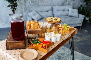 In a cozy living room, there is a table laid out with a delightful variety of food and drinks enticingly arranged on it, perfect for entertaining guests or enjoying a meal together photo