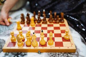 A person is actively engaged in playing a game of chess on a beautifully crafted wooden chess board, focusing intently on their next strategic moves and decisions in the game photo