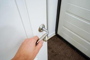 A person is currently engaged in the action of opening a door, using a key to unlock it, effectively showcasing the interaction with the door mechanism for access and entry photo