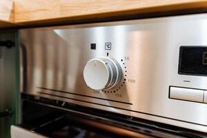 This image shows a closeup view of a shiny stainless steel oven installed in a modern kitchen, highlighting its sleek design and functionality as an essential home appliance photo