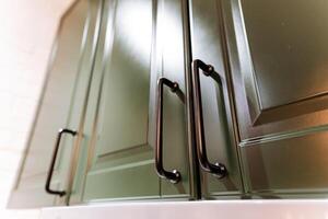 This image captures a detailed closeup view of vibrant green cabinets, elegantly complemented by sleek black handles that highlight their modern design and functionality photo