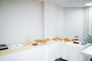 There is a buffet table filled with a wide variety of delicious foods set up in a spacious room, creating an inviting atmosphere for guests to enjoy their meals together photo