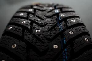 This is a detailed close up image of a tire that features spikes on its surface, showcasing its unique design and rugged appearance in the realm of automotive accessories photo