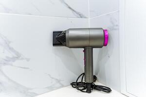 In the corner of a bathroom, a hair dryer is positioned, quietly waiting to be used, showcasing both practicality and the necessity of personal grooming in our daily routines photo