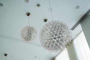 In the beautifully designed room, there are two elegant chandeliers hanging gracefully from the ceiling, adding a touch of sophistication and charm to the overall ambiance of the space photo