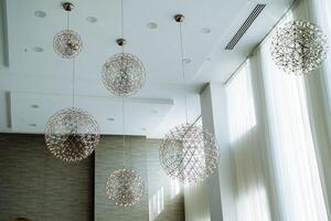 Elegant pendant lights beautifully illuminate a modern space, enhanced by the soft, warm glow of natural light streaming through the windows photo