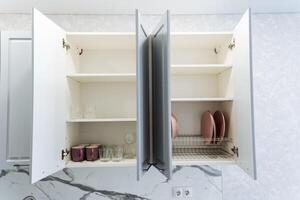 A kitchen cabinet featuring its doors wide open, showcasing a dish drying rack placed inside, indicating a space actively used for preparing meals and cleaning up afterward photo