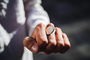A person confidently holds a shiny, gleaming coin in their hand, drawing attention to the beautifully manicured fingers and thumb, showcasing a fascinating interplay with their wrist photo