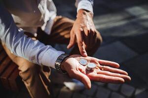 A man confidently and proudly showcases his collection of valuable coins in one hand, gesturing with his index finger to emphasize their significance, beauty, and historical value photo